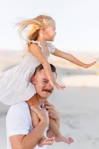 Daughter rides dad's shoulders while dancing in the wind