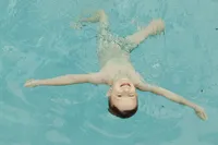Boy swims happily in their backyard during their at home family photo session near houston texas