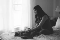 A film photo of a mother looking at her newborn baby in her bedroom during her at home newborn photo session near houston texas