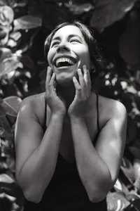 A mother laughs and holds her face gazing into the sunshine during her maternity photos in houston texas