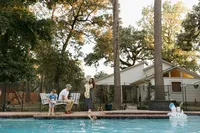 A family enjoys an evening by their backyard pool during their at home family photo session near houston texas