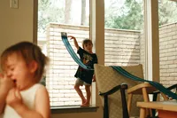 boy plays with hot wheel cars by the window during an at home family photo session in houston texas