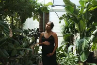 A mother holds her belly and basks in the sunshine during her maternity photo session in houston texas