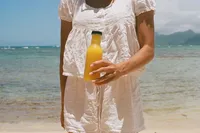 Woman holding fresh fruit juice at the beach on Oahu