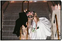 A bride and groom kiss across a barrier in the middle of a staircase, by wedding film photographer Grace Wan.