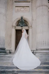 Bride seen from behind in a flowing gown and veil before a grand stone doorway