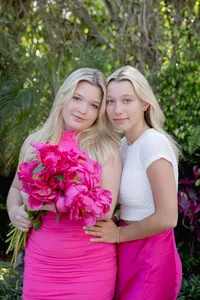 Sisters' branding portrait in matching pink outfits holding peonies