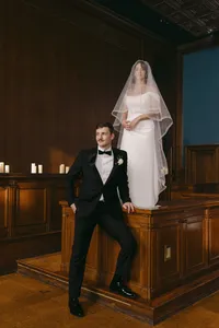 Editorial portrait of Grace in a veil standing on a wood-panelled platform beside Jacob in a tuxedo, by Dove and Fox