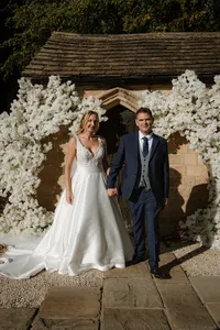 couple leaving wedding venue with white floral display around the entrance