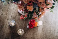 close up of pink and orange floral arrangement and candles