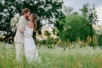 Bride and groom embracing each other while sharing a kiss in a flower field during their wedding portraits.
