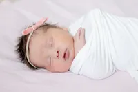 Close-up of sleeping newborn in a white wrap with headband