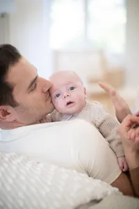 Father kissing his baby's cheek during a family portrait session