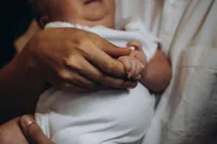 Close up of a mother holding hands with her newborn baby, by Grand Rapids family photographer Grace Wan.