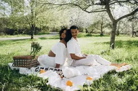 Grand Rapids maternity photography of a husband and wife sitting back to back on a white blanket.