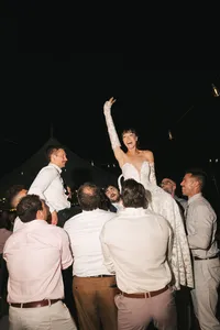 bride being lifted at nighttime reception - Photograph of bride raised up by male guests celebrating at nighttime reception with warm ambient lighting