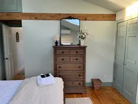 Primary bedroom with wood dresser and exposed beam at Brookside Retreat