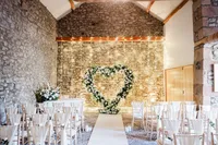 heart-shaped white rose wedding ceremony arch with fairy lights backdrop
