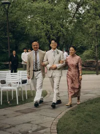 A groom walks with his mother and father on both sides of him, captured by Michigan wedding photographer Grace Wan.