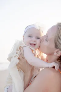 Mother kissing her baby's cheek during a beach portrait session