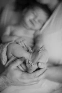 Close-up of a newborn's foot held gently, photographed in black and white