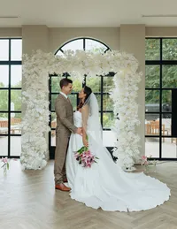 couple in front of white square wedding floral arch