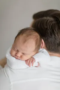 Newborn baby sleeping on their father's shoulder during a studio portrait session