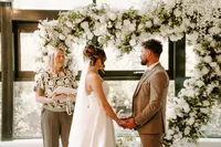 Wedding couple exchanging vows in front of a heart-shaped white rose wedding arch