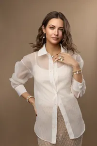 Woman's branding portrait in a sheer blouse against warm studio tones