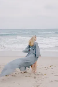 Woman walking the shoreline in a flowing blue dress during her beach portrait session