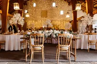 fairy lights, white blossom tree and white floral table decor in wedding venue