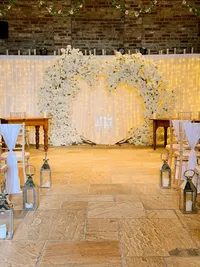 white floral wedding ceremony arch with fairy lights and chair styling