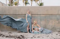 Siblings in matching flowy blue dresses posing at the beach