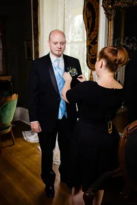 Wedding planner with Weddings & Events by Raina pins on groom's boutonniere