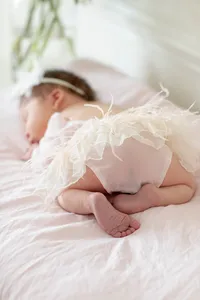 Sleeping newborn baby wearing feather-trimmed bloomers
