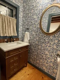 Powder room vanity with blue patterned wallpaper at Brookside Retreat