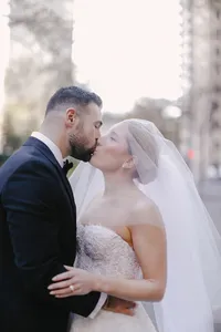 Bride and groom share a kiss on a city street with soft golden light behind them