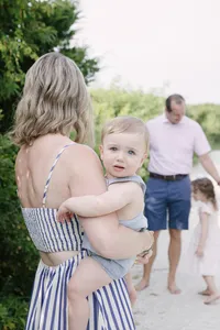 Mother carrying her child along a dune grass path