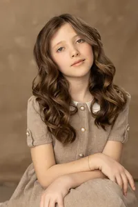 Girl's studio portrait wearing a tailored dress with pearl button details