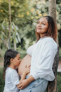 girl kissing pregnant moms belly