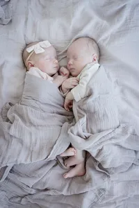 Newborn twins swaddled together in grey