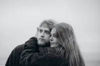 Black and white close up couples photo of a woman gently holding her partner's face to hers.