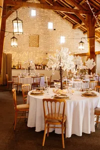 fairy lights, white blossom tree and white floral table decor in wedding venue