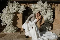 bride and groom outside Yorkshire wedding venue with white floral display around the entrance