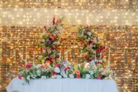 colourful floral wedding table decor and floral wedding arch with fairy light backdrop