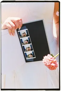 Close up of the bride holding a photobooth strip of her and her husband taped to her book of vows.