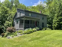 Side exterior of Brookside Retreat surrounded by summer greenery