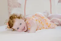 Toddler smiling in a yellow outfit during a family portrait session