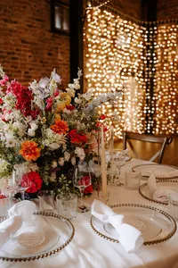 colourful floral wedding table centrepiece with fairy light backdrop