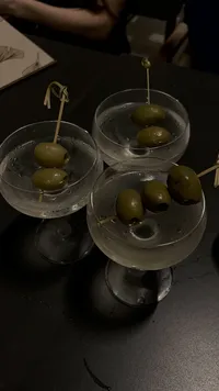close up of olives in three glass martini glasses